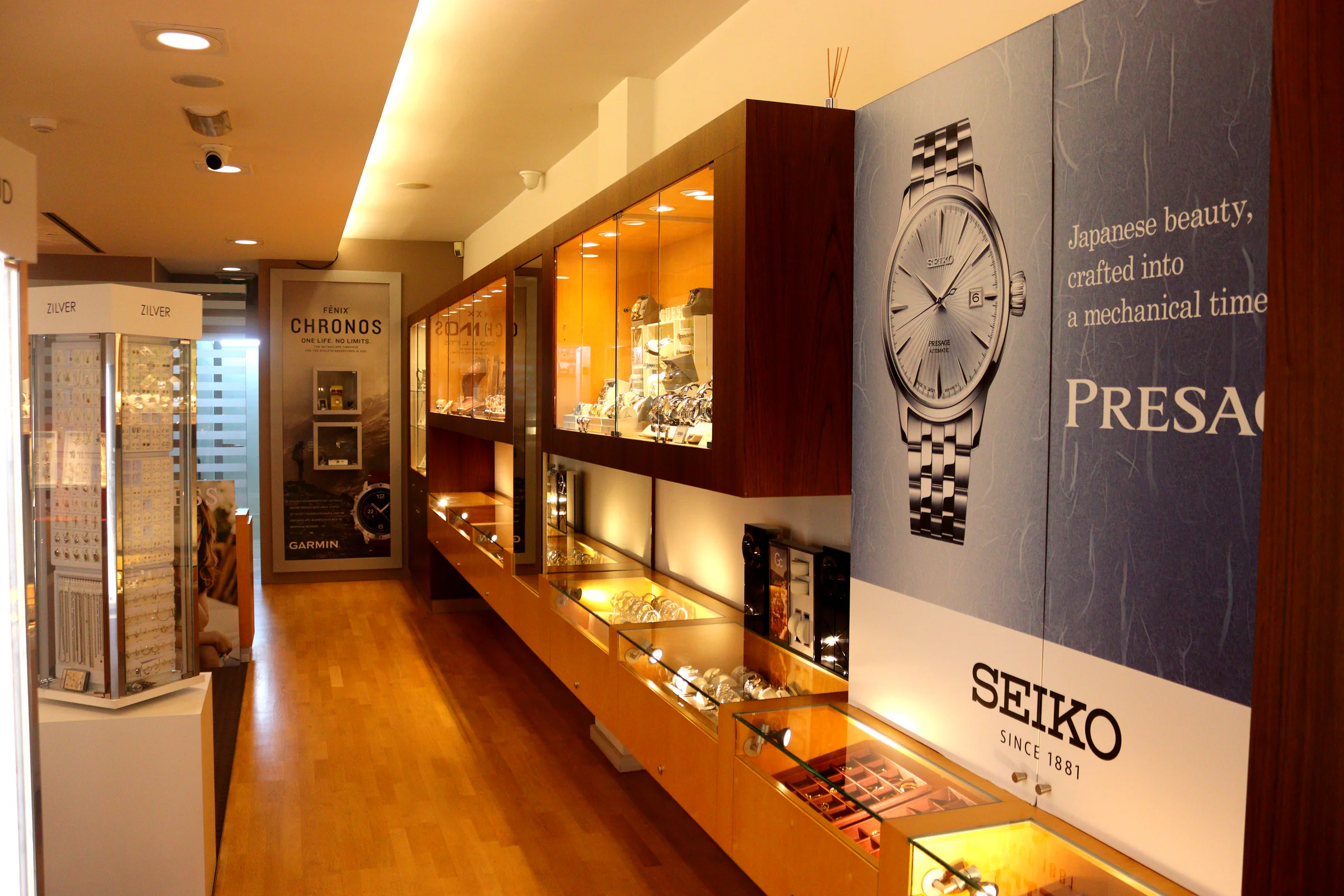 Interieur van Symfonie Juwelier: verlichte vitrines met sieraden en een Seiko display, met verse bloemen op de toonbank